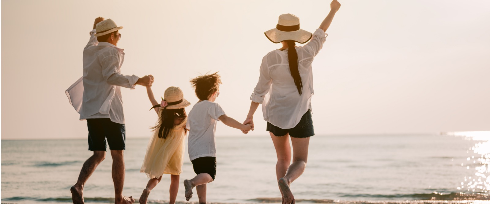 A family of four are enjoying a walk on the beach. 