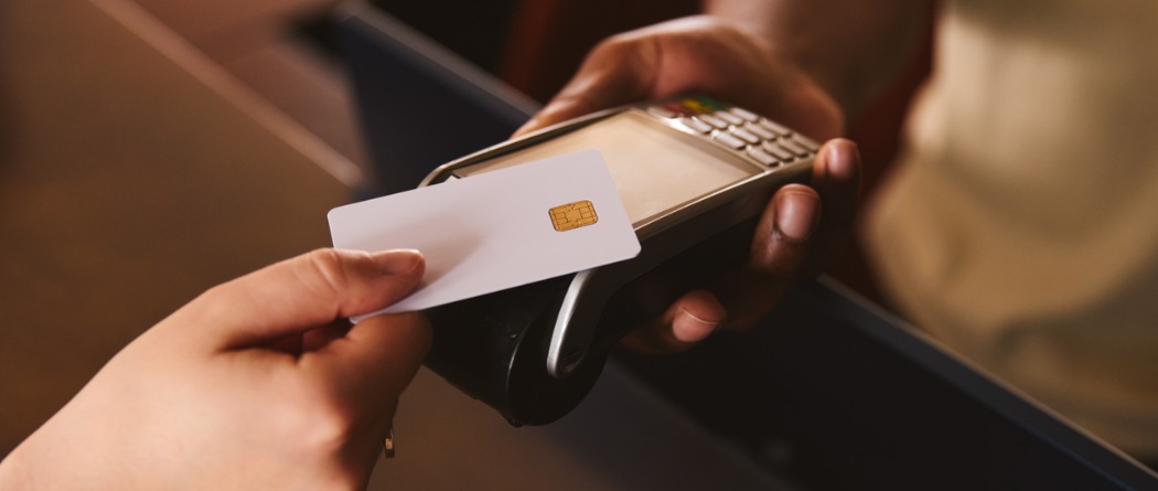 A picture of a debit card being held over a tap to pay terminal 